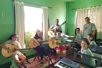 Alunos e professores com violões e teclado em sala de aula